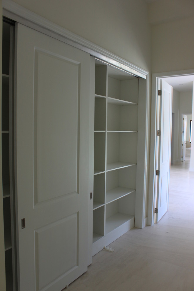 Design ideas for a mid-sized transitional gender-neutral built-in wardrobe in Miami with shaker cabinets, white cabinets, marble floors and beige floor.