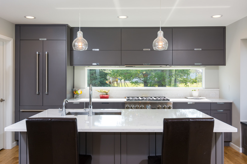 Photo of a mid-sized contemporary single-wall eat-in kitchen in Detroit with an undermount sink, flat-panel cabinets, grey cabinets, quartz benchtops, white splashback, stone slab splashback, stainless steel appliances, light hardwood floors, with island, brown floor and white benchtop.