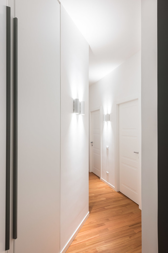 Photo of a contemporary hallway in Rome with white walls and light hardwood floors.