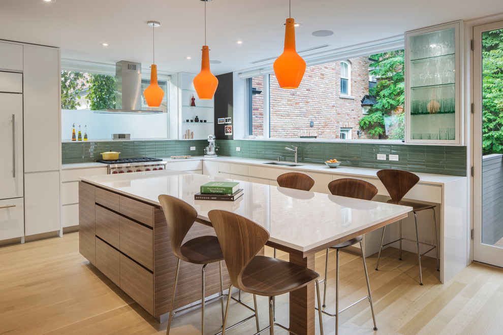 Inspiration for a small contemporary l-shaped open plan kitchen in Toronto with an undermount sink, flat-panel cabinets, white cabinets, green splashback, glass tile splashback, panelled appliances, light hardwood floors and with island.