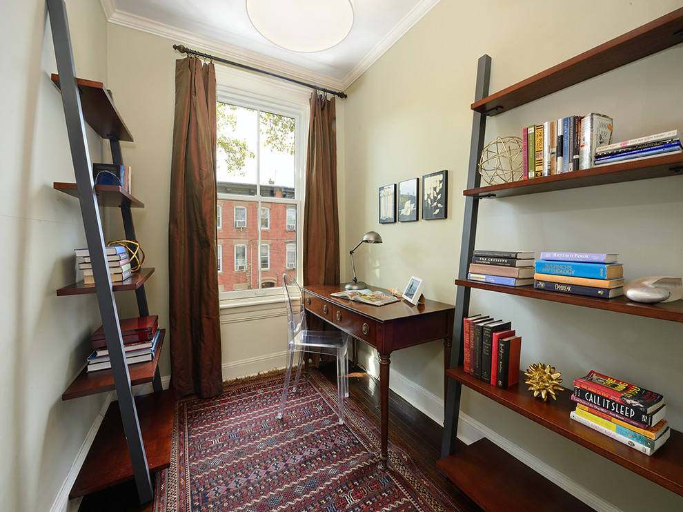 Photo of a traditional study room in New York with beige walls, dark hardwood floors and a freestanding desk.