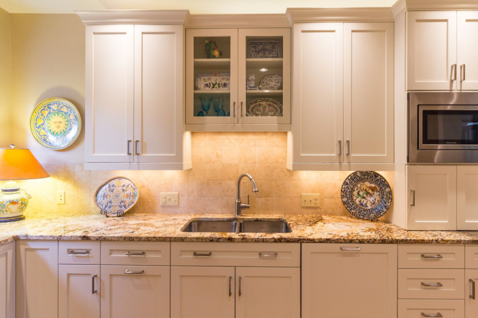 Large transitional u-shaped brown floor and medium tone wood floor enclosed kitchen photo in Denver with a double-bowl sink, shaker cabinets, white cabinets, granite countertops, beige backsplash, ceramic backsplash, stainless steel appliances and an island