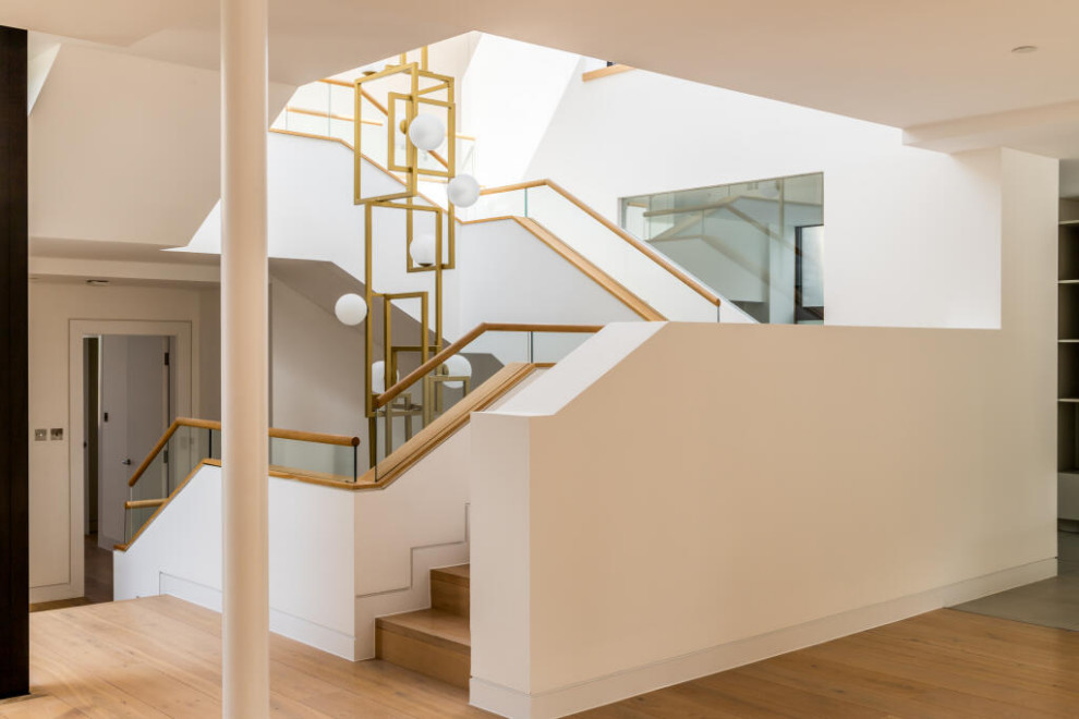 This is an example of a small modern wood curved wood railing staircase spindle in London with wood risers.