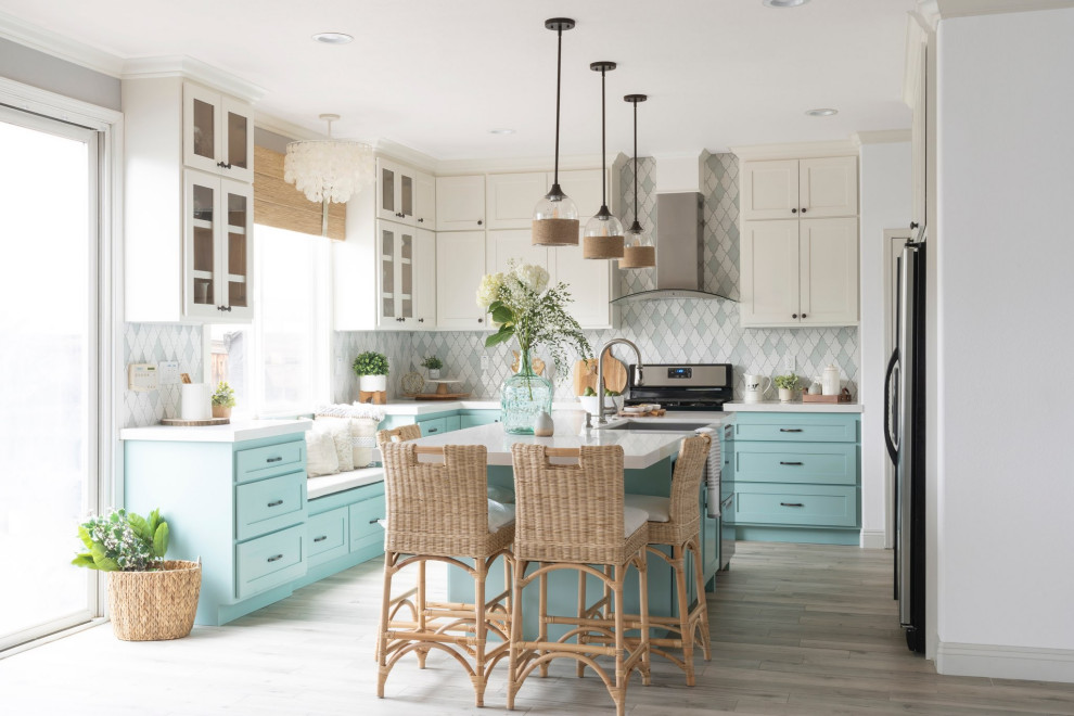 Inspiration for a beach style kitchen in Los Angeles with a farmhouse sink, shaker cabinets, turquoise cabinets, multi-coloured splashback, stainless steel appliances, medium hardwood floors, a peninsula, brown floor and white benchtop.