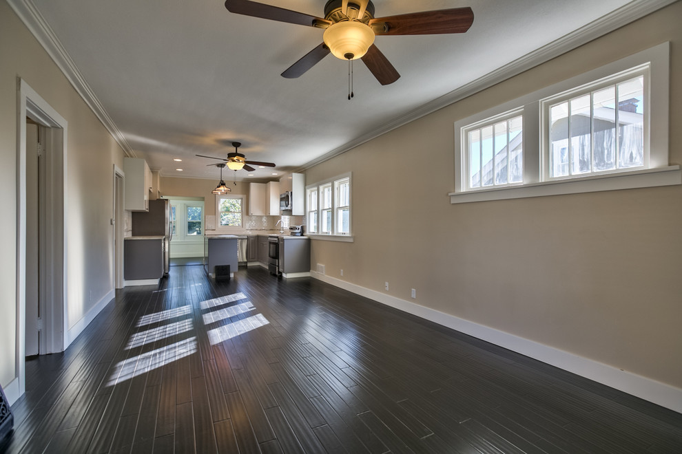 This is an example of a transitional open concept living room in Omaha with beige walls and dark hardwood floors.
