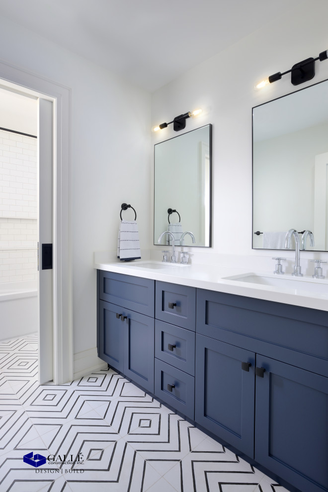 Cette image montre une salle de bain traditionnelle de taille moyenne pour enfant avec un placard à porte shaker, des portes de placard bleues, une baignoire en alcôve, un plan de toilette en marbre, un plan de toilette blanc, meuble double vasque et meuble-lavabo encastré.