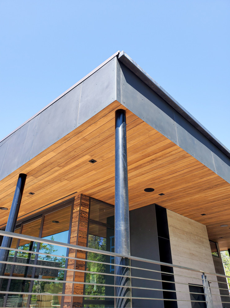 На фото: двухэтажный частный загородный дом в стиле модернизм с комбинированной облицовкой и металлической крышей с