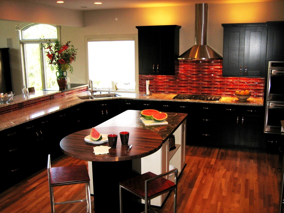 Eclectic u-shaped medium tone wood floor eat-in kitchen photo in Other with an undermount sink, shaker cabinets, dark wood cabinets, granite countertops, red backsplash, glass tile backsplash, stainless steel appliances and an island