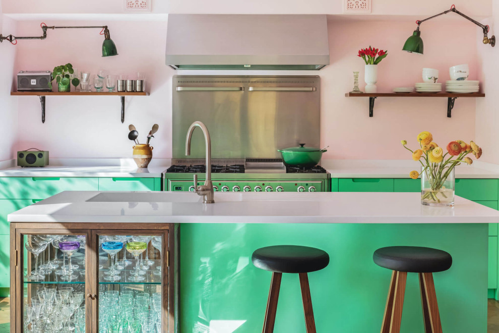 This is an example of a medium sized bohemian single-wall kitchen/diner in London with flat-panel cabinets, green cabinets, composite countertops, an island and white worktops.