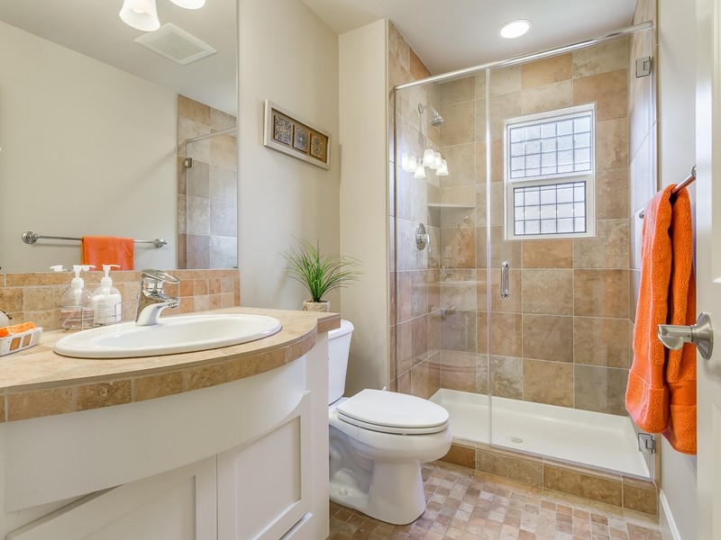 Mid-sized traditional 3/4 bathroom in Seattle with a drop-in sink, recessed-panel cabinets, white cabinets, limestone benchtops, an alcove shower, a two-piece toilet, stone tile, beige walls, terra-cotta floors and beige tile.