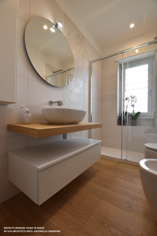 Photo of a large modern shower room bathroom in Other with flat-panel cabinets, white cabinets, a corner shower, white tiles, porcelain tiles, white walls, light hardwood flooring, a vessel sink, wooden worktops, brown floors, a sliding door, brown worktops, a single sink and a floating vanity unit.