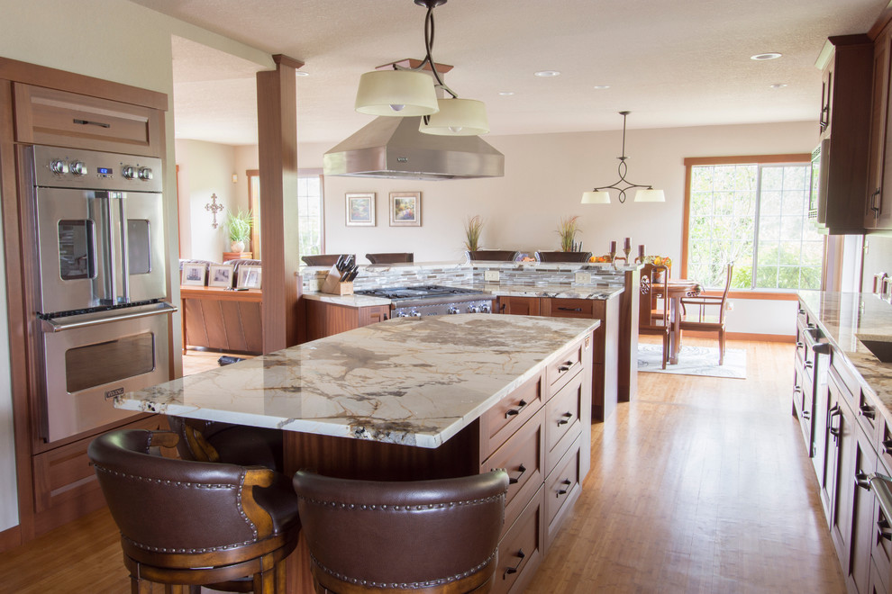 Mid-sized elegant galley medium tone wood floor and brown floor open concept kitchen photo in Seattle with an undermount sink, recessed-panel cabinets, medium tone wood cabinets, marble countertops, beige backsplash, glass tile backsplash, stainless steel appliances and two islands