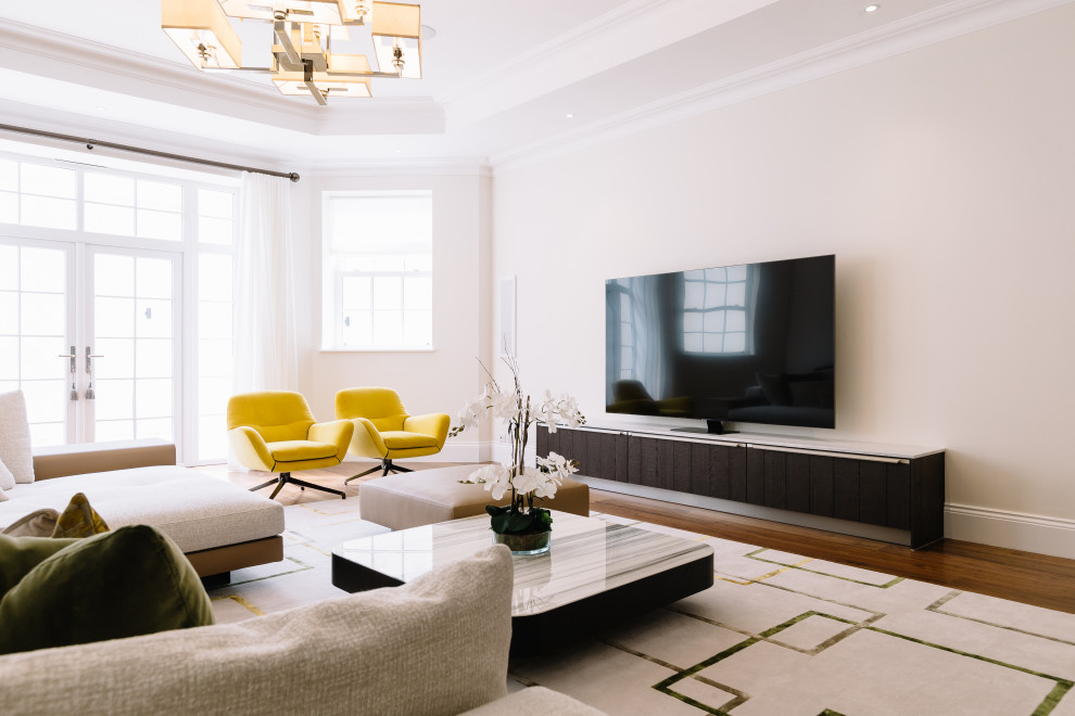 This is an example of a contemporary living room in Surrey with beige walls, medium hardwood floors, a freestanding tv and brown floor.