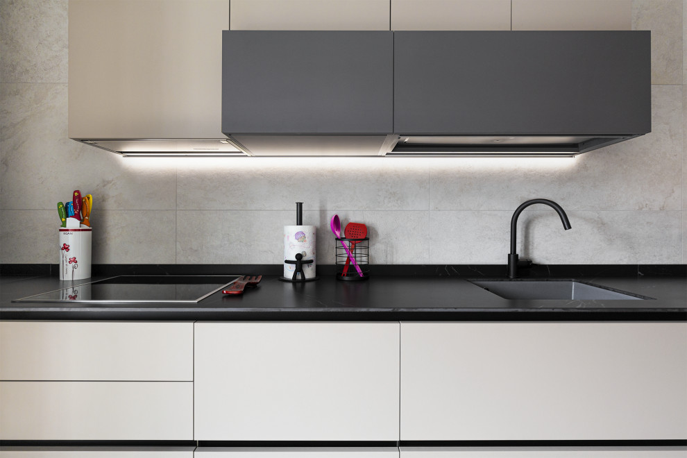 This is an example of a large contemporary u-shaped separate kitchen in Other with an integrated sink, flat-panel cabinets, beige cabinets, solid surface benchtops, black splashback, porcelain splashback, black appliances, porcelain floors, no island, brown floor, black benchtop and recessed.