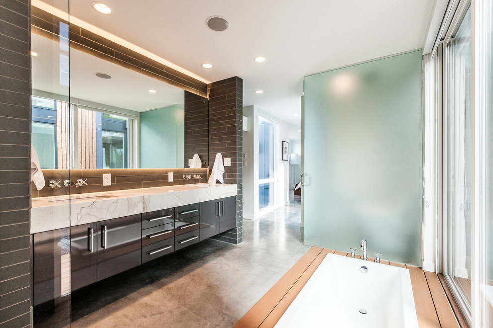 This is an example of a contemporary master bathroom in Seattle with an undermount sink, flat-panel cabinets, brown cabinets, a drop-in tub, gray tile and concrete floors.