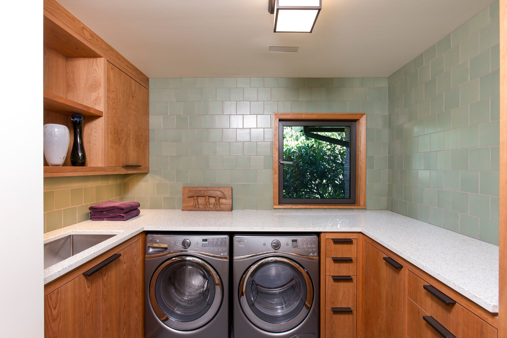 Inspiration for a mid-sized contemporary u-shaped dedicated laundry room in Portland with a drop-in sink, flat-panel cabinets, medium wood cabinets, recycled glass benchtops, green walls and a side-by-side washer and dryer.