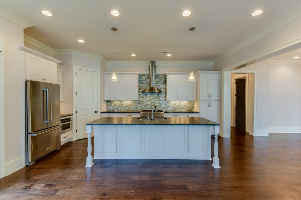 Example of a mid-sized transitional l-shaped medium tone wood floor eat-in kitchen design in Charlotte with a drop-in sink, recessed-panel cabinets, white cabinets, quartzite countertops, gray backsplash, glass tile backsplash, stainless steel appliances and an island