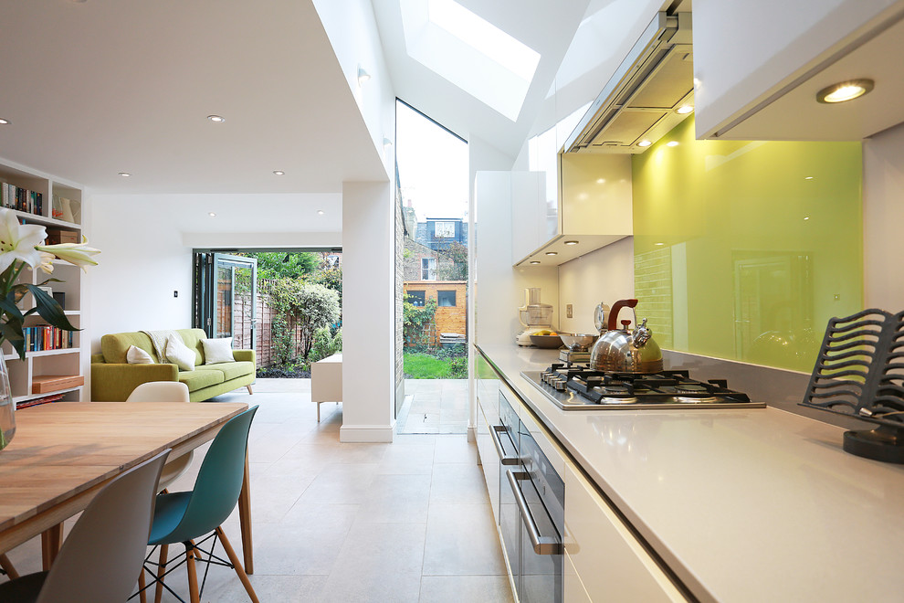 Photo of a large contemporary eat-in kitchen in London with glass tile splashback, porcelain floors, no island, an undermount sink, flat-panel cabinets, white cabinets, quartz benchtops, yellow splashback, stainless steel appliances and beige floor.