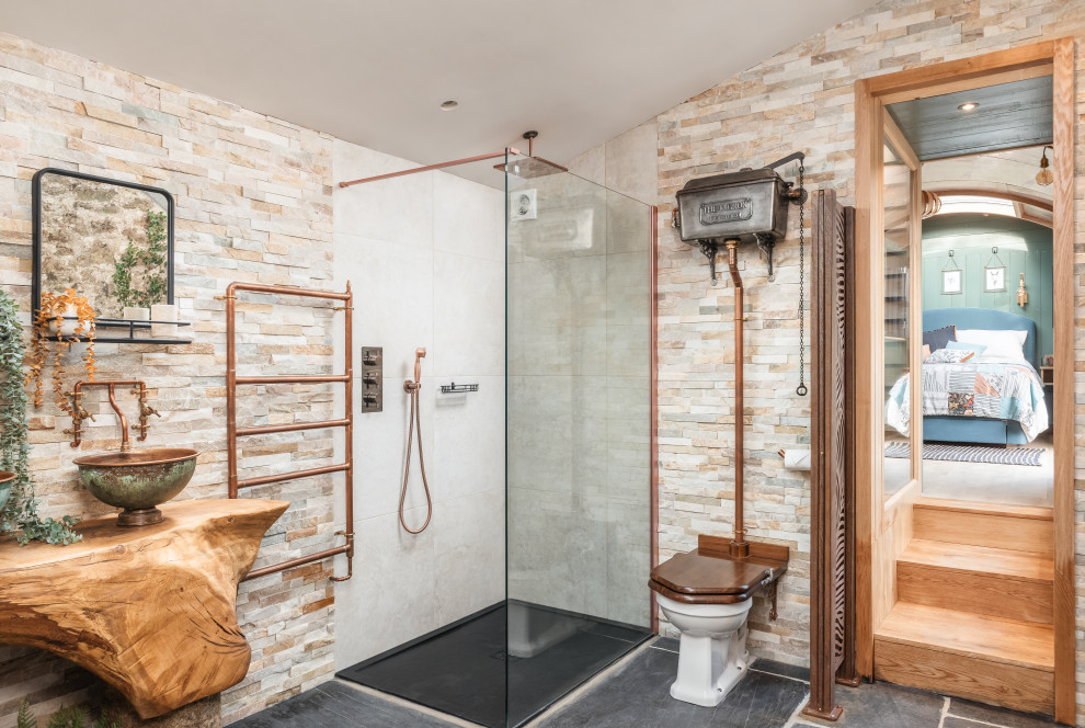 Mittelgroßes Landhausstil Duschbad mit freistehender Badewanne, offener Dusche, Toilette mit Aufsatzspülkasten, beigen Fliesen, Steinfliesen, beiger Wandfarbe, Waschtisch aus Holz, grauem Boden, offener Dusche und Doppelwaschbecken in Cornwall