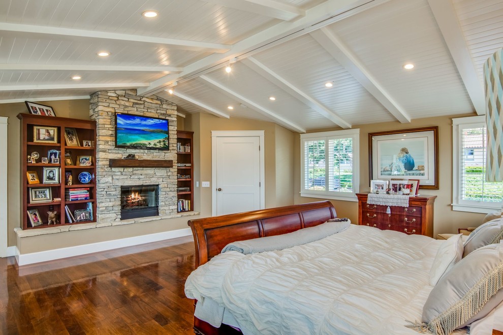 Design ideas for a large arts and crafts master bedroom in Los Angeles with beige walls, medium hardwood floors, a standard fireplace, a stone fireplace surround and brown floor.