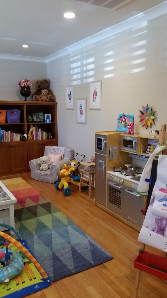 This is an example of a mid-sized transitional gender-neutral kids' room in San Francisco with grey walls and light hardwood floors.