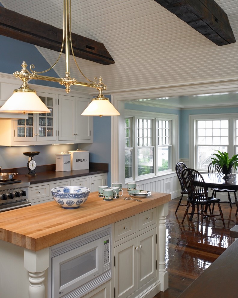 Photo of a mid-sized beach style u-shaped eat-in kitchen in Boston with beaded inset cabinets, white cabinets, wood benchtops, stainless steel appliances, dark hardwood floors and with island.