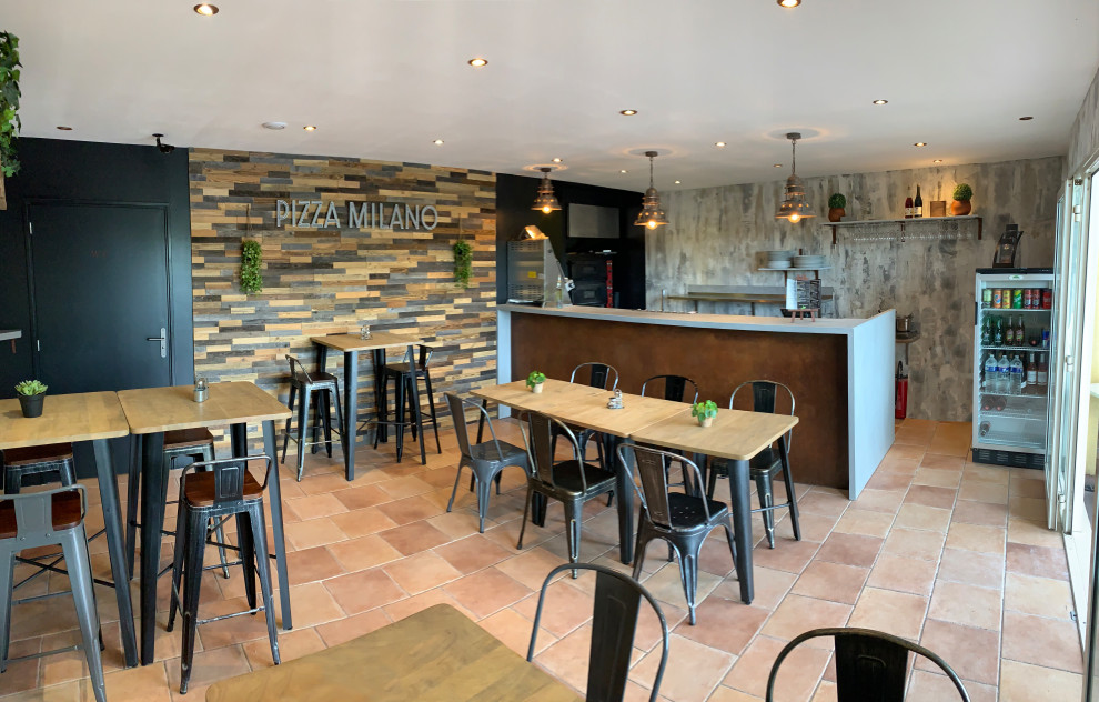 Immagine di una sala da pranzo aperta verso il soggiorno industriale di medie dimensioni con pareti grigie, pavimento in terracotta e pareti in legno