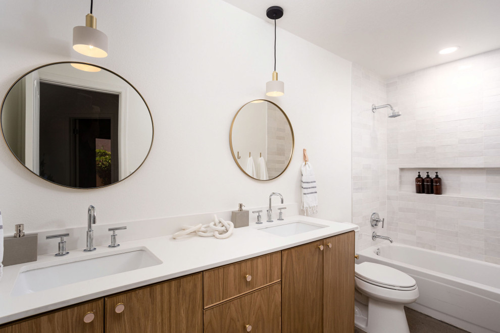 Design ideas for a mid-sized scandinavian kids bathroom in Phoenix with flat-panel cabinets, light wood cabinets, a shower/bathtub combo, a two-piece toilet, white tile, ceramic tile, white walls, concrete floors, an undermount sink, engineered quartz benchtops, white benchtops, a niche, a double vanity and a floating vanity.