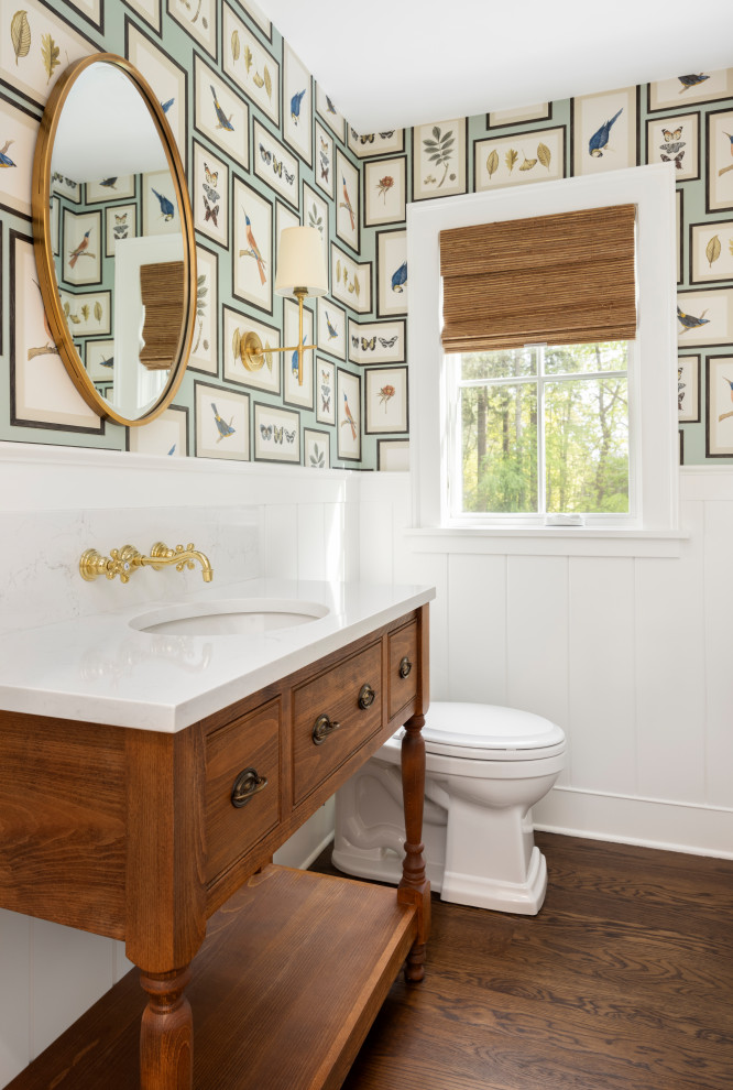 Cette image montre un petit WC et toilettes traditionnel avec un mur multicolore, un sol en bois brun, un lavabo encastré, un plan de toilette en quartz modifié, un plan de toilette blanc, meuble-lavabo sur pied et du papier peint.