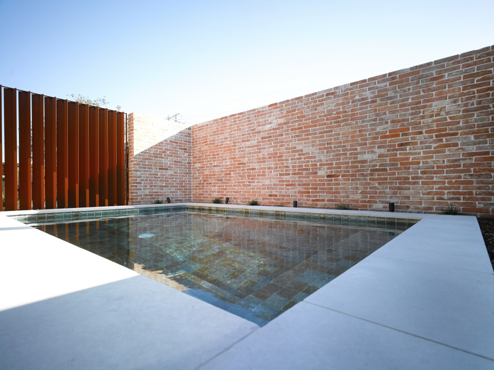 This is an example of a small industrial backyard rectangular aboveground pool in Gold Coast - Tweed with with privacy feature and natural stone pavers.