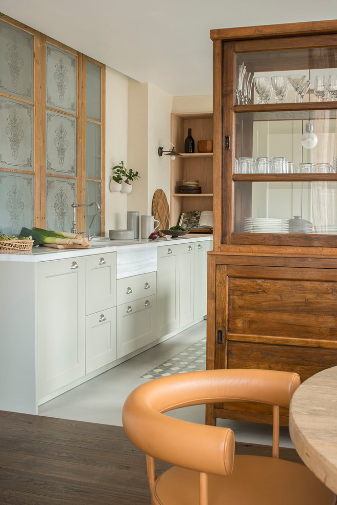 Inspiration for a mid-sized mediterranean l-shaped open plan kitchen in Barcelona with a drop-in sink, raised-panel cabinets, beige cabinets, limestone benchtops, ceramic floors, with island, multi-coloured floor and grey benchtop.