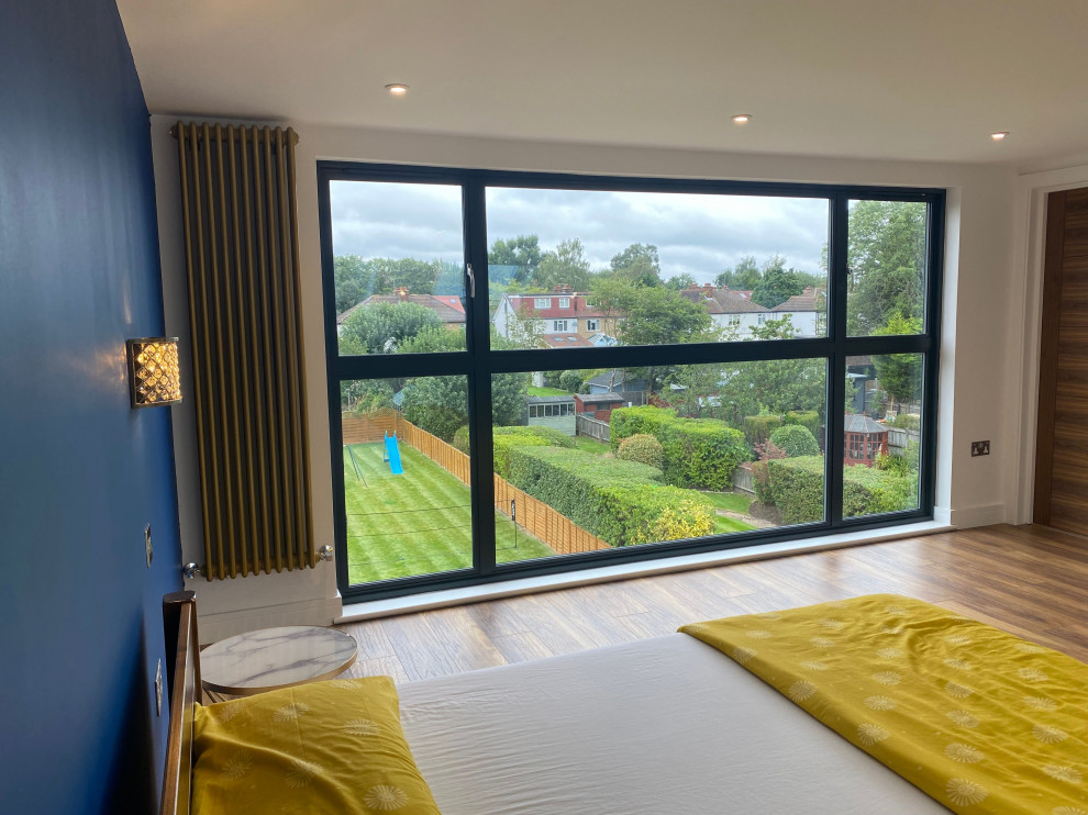 На фото: хозяйская спальня среднего размера на мансарде с синими стенами, полом из бамбука, коричневым полом, любым потолком и любой отделкой стен с