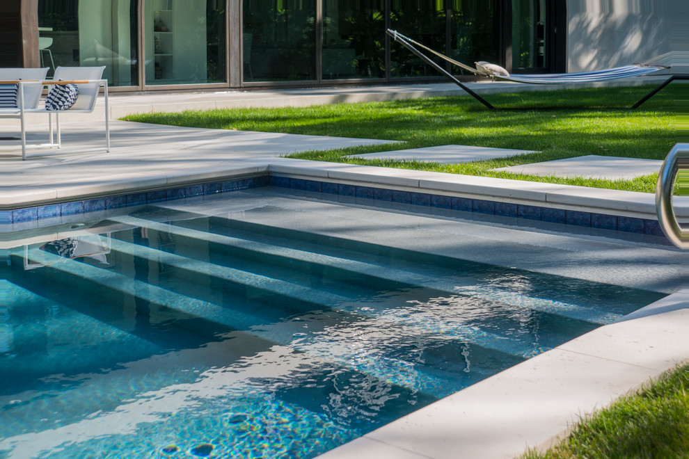 Inspiration for a small modern backyard rectangular lap pool in Chicago with natural stone pavers.