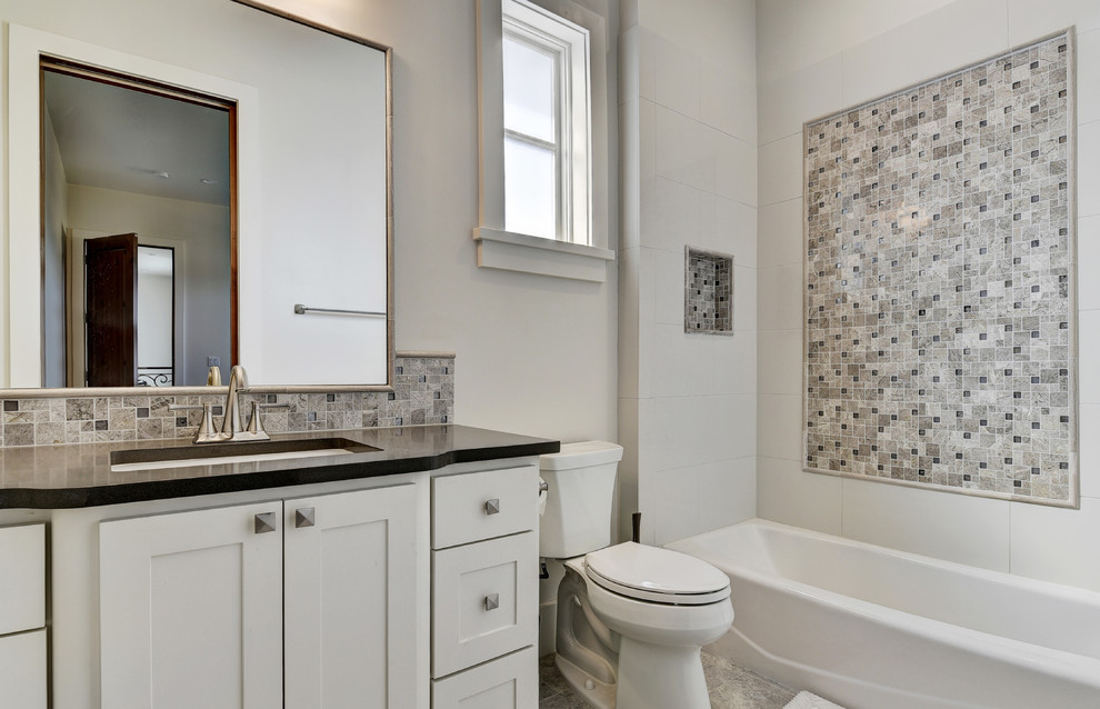Design ideas for a mid-sized transitional kids bathroom in Austin with shaker cabinets, grey cabinets, an alcove tub, a shower/bathtub combo, a two-piece toilet, beige tile, mosaic tile, grey walls, porcelain floors, an undermount sink, solid surface benchtops, brown floor and a shower curtain.