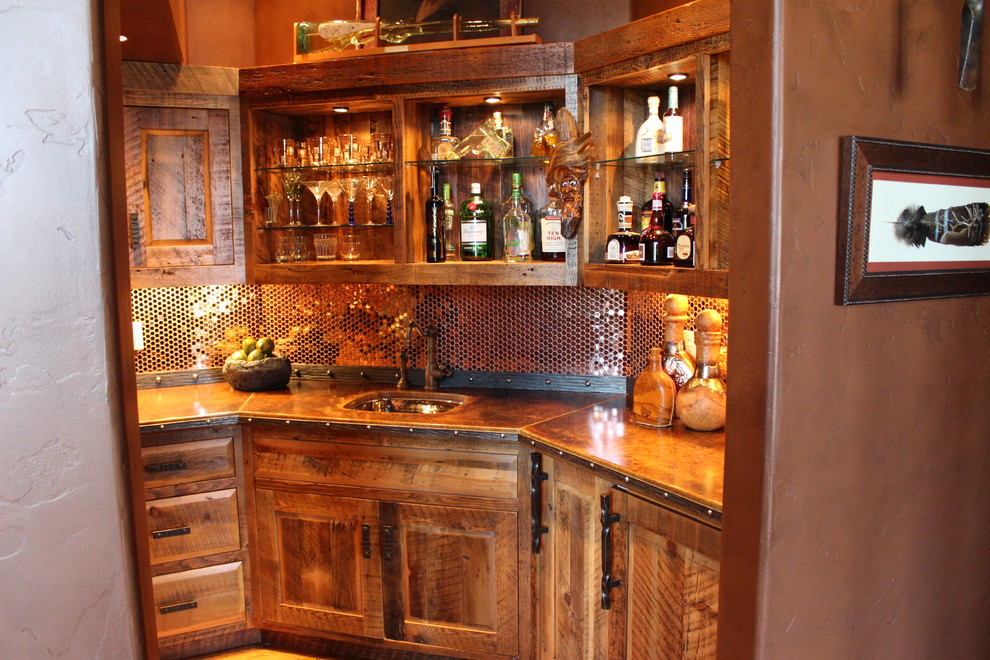This is an example of a mid-sized l-shaped wet bar in Other with an undermount sink, raised-panel cabinets, distressed cabinets, concrete benchtops, multi-coloured splashback, metal splashback and dark hardwood floors.