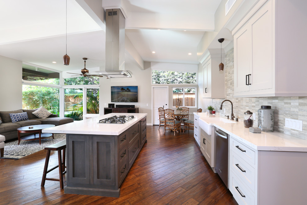 Photo of a transitional galley open plan kitchen in Orange County with a farmhouse sink, shaker cabinets, white cabinets, beige splashback, stainless steel appliances, medium hardwood floors and with island.
