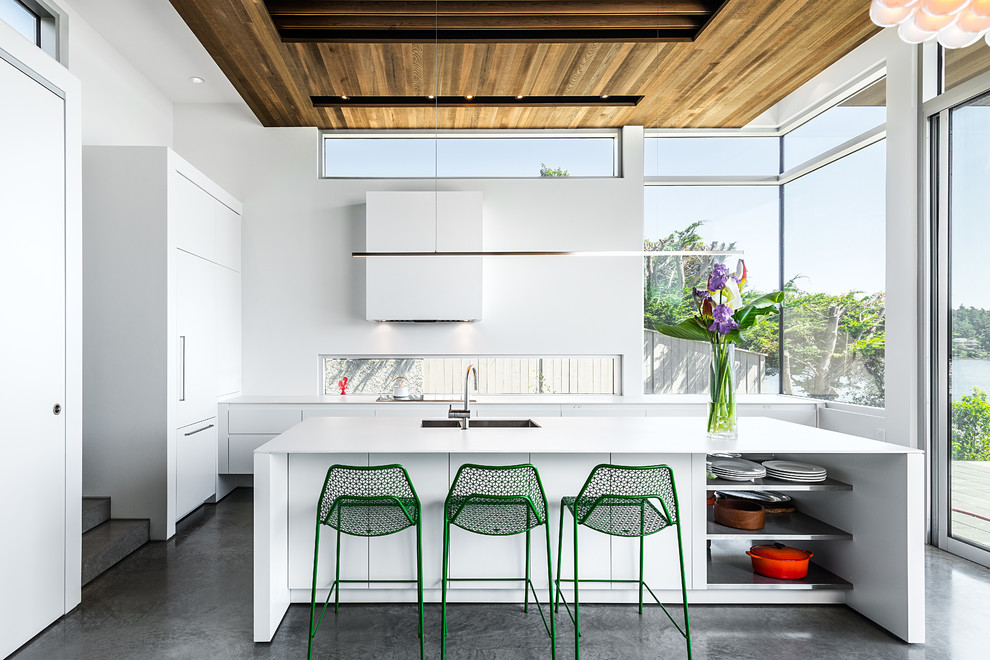 Trendy l-shaped concrete floor kitchen photo in Vancouver with an undermount sink, flat-panel cabinets, white cabinets, paneled appliances and an island