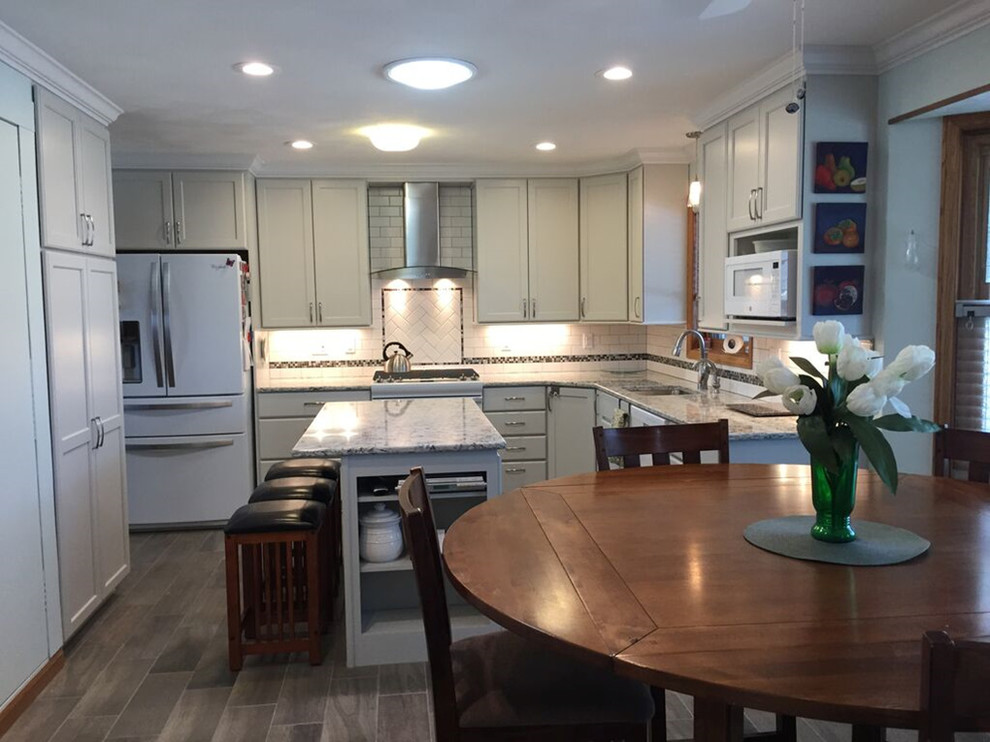 Kitchen - transitional u-shaped ceramic tile kitchen idea with an undermount sink, recessed-panel cabinets, white backsplash, subway tile backsplash, white appliances and an island