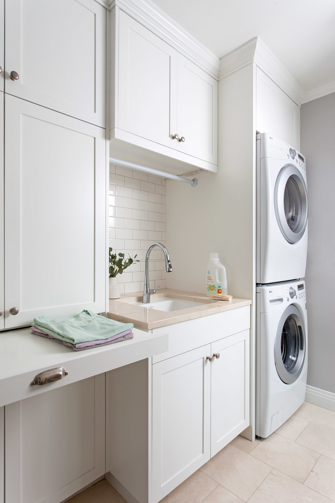 Traditional dedicated laundry room in Austin with an undermount sink, shaker cabinets, white cabinets, grey walls and a stacked washer and dryer.