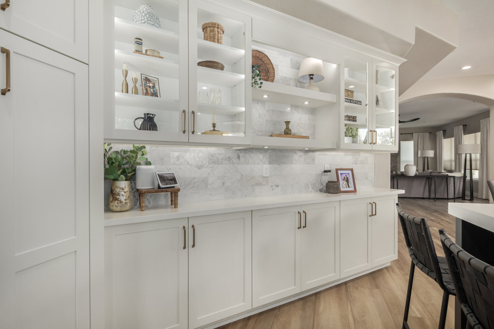 Inspiration for a mid-sized transitional u-shaped porcelain tile and brown floor enclosed kitchen remodel in Phoenix with a farmhouse sink, shaker cabinets, white cabinets, quartz countertops, white backsplash, marble backsplash, stainless steel appliances, an island and white countertops