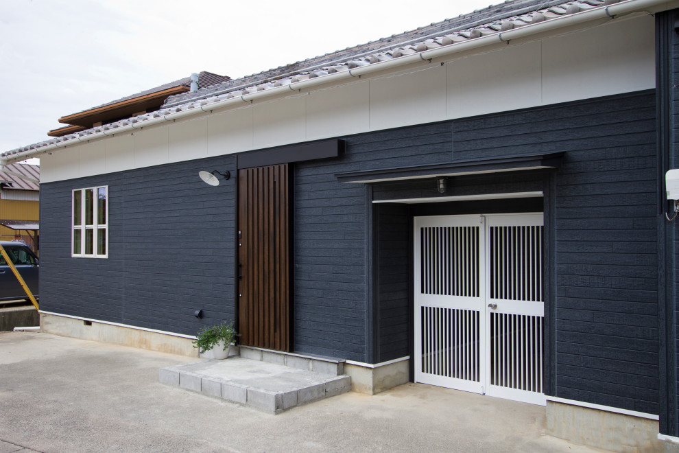 Diseño de fachada negra costera de tamaño medio de una planta con tejado a dos aguas, microcasa y tejado de teja de barro