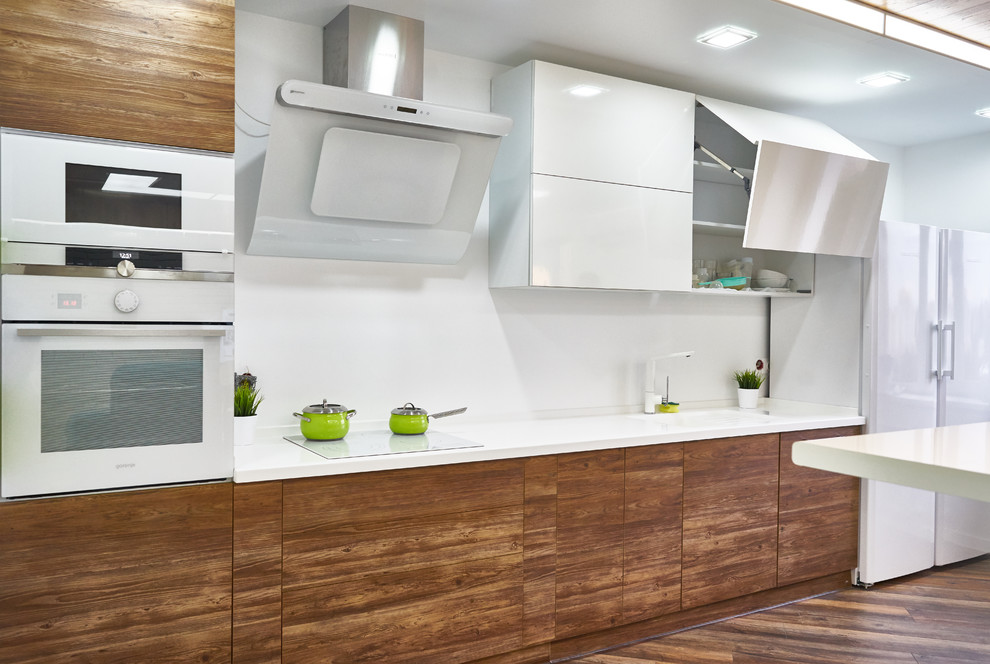 Design ideas for a contemporary single-wall kitchen in Moscow with a drop-in sink, flat-panel cabinets, medium wood cabinets, white splashback, white appliances, white benchtop and medium hardwood floors.