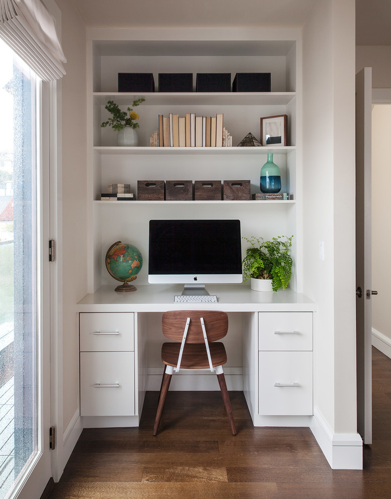 This is an example of a transitional study room in San Francisco with white walls, medium hardwood floors and a built-in desk.