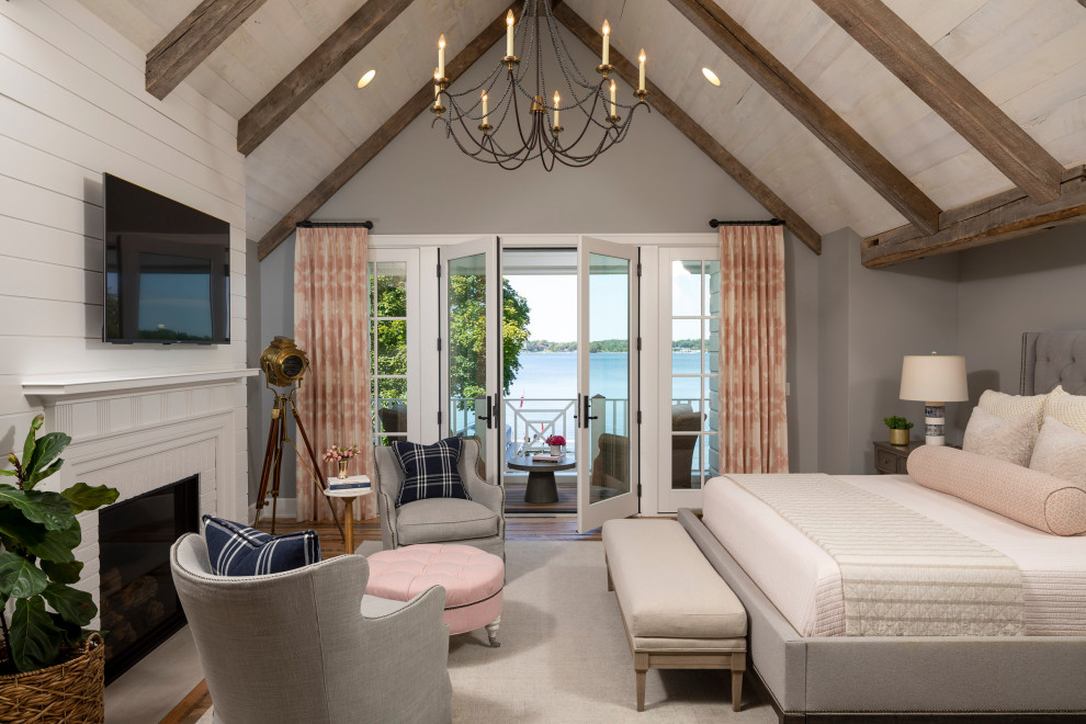 Inspiration for a large coastal master bedroom in Minneapolis with grey walls, medium hardwood flooring, a standard fireplace, a brick fireplace surround, brown floors and a vaulted ceiling.