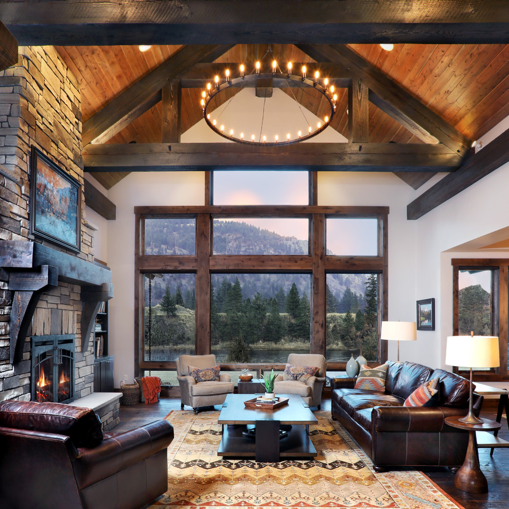 Inspiration for a country open concept living room in Other with white walls, dark hardwood floors, a standard fireplace, a stone fireplace surround and brown floor.