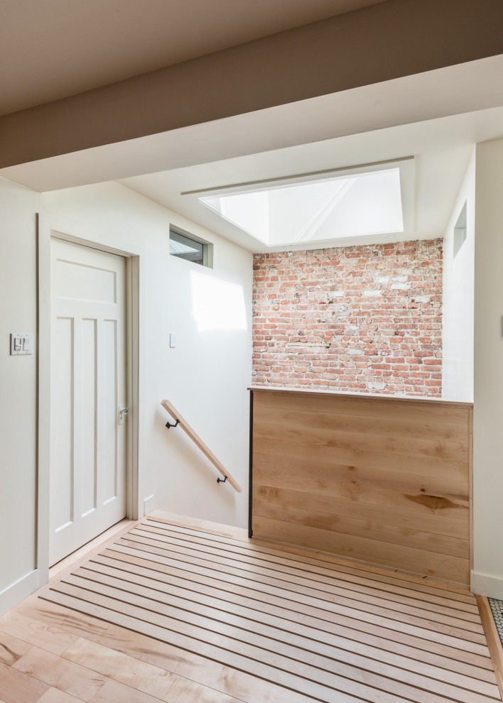 Foto de escalera en U minimalista de tamaño medio con barandilla de madera y ladrillo