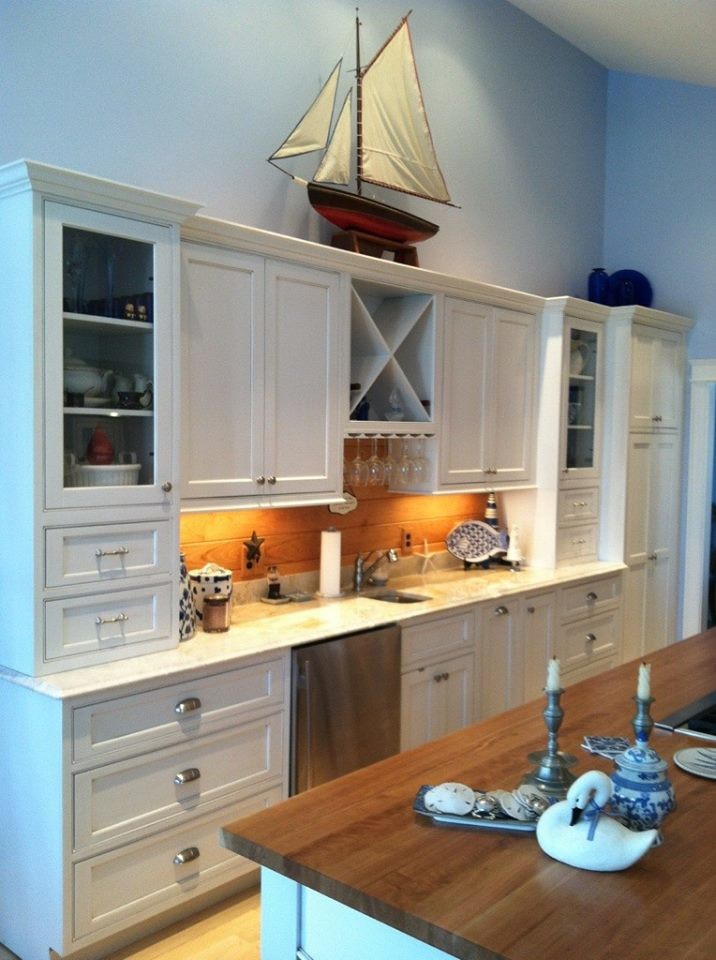 Example of a transitional l-shaped light wood floor eat-in kitchen design in Boston with an undermount sink, shaker cabinets, white cabinets, granite countertops, stainless steel appliances, an island, brown backsplash and wood backsplash