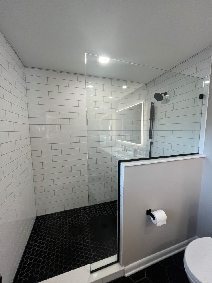 На фото: главная ванная комната среднего размера в стиле модернизм с фасадами в стиле шейкер, светлыми деревянными фасадами, душем в нише, раздельным унитазом, белой плиткой, плиткой кабанчик, серыми стенами, полом из керамогранита, монолитной раковиной, столешницей из искусственного кварца, черным полом, душем с распашными дверями, белой столешницей, нишей, тумбой под одну раковину и напольной тумбой с