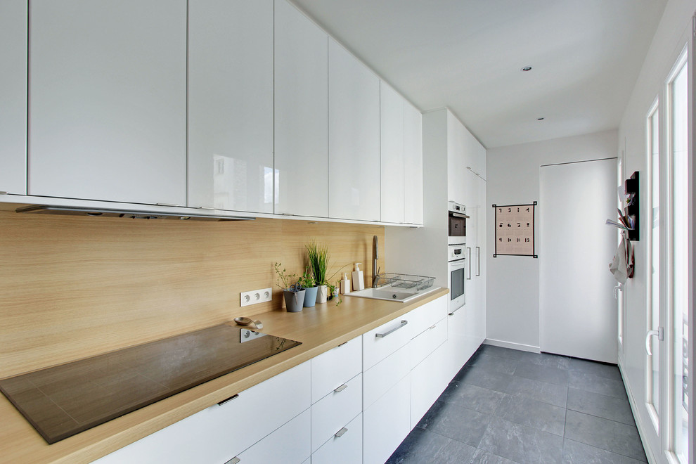 Design ideas for a mid-sized contemporary single-wall separate kitchen in Paris with a drop-in sink, flat-panel cabinets, white cabinets, wood benchtops, brown splashback, no island, white appliances and ceramic floors.