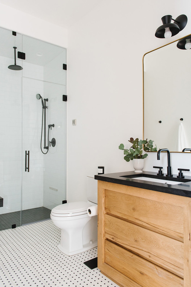Inspiration for a mid-sized transitional 3/4 bathroom in Salt Lake City with light wood cabinets, an alcove shower, white tile, ceramic tile, white walls, a hinged shower door, black benchtops, a two-piece toilet, an undermount sink, multi-coloured floor and flat-panel cabinets.